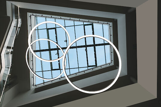 Three ring-shaped Ringo Star LED pendant lights from Lightnet in the atrium of Delbrück Town Hall