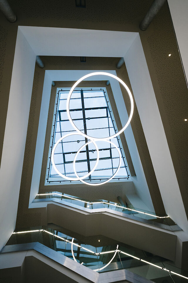 Three Ringo Star LED pendant lights from Lightnet illuminate the modern stairwell in Delbrück Town Hall