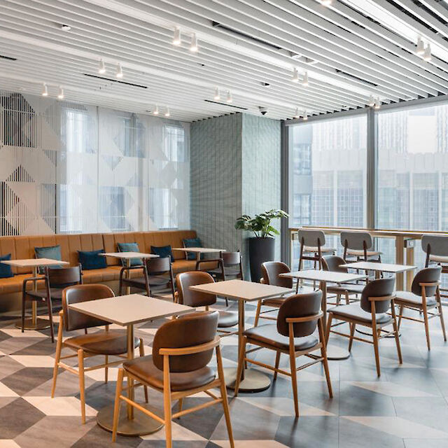 Modern lounge area with geometric flooring, wooden furniture, and large windows.