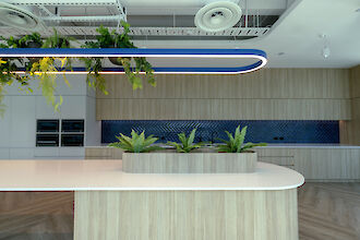 Blue Liquid Line pendant light above kitchen island with plants, wooden fronts and blue tiled backsplash