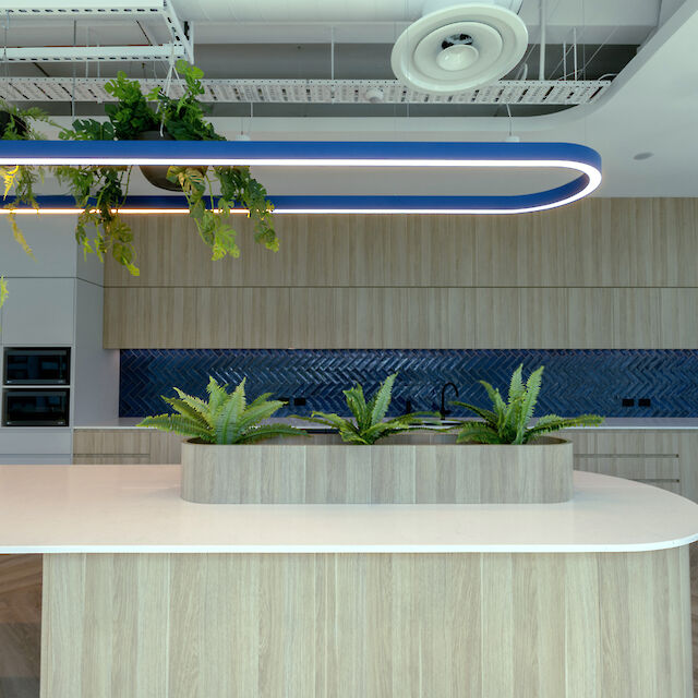 Blue Liquid Line pendant light above kitchen island with plants, wooden fronts and blue tiled backsplash