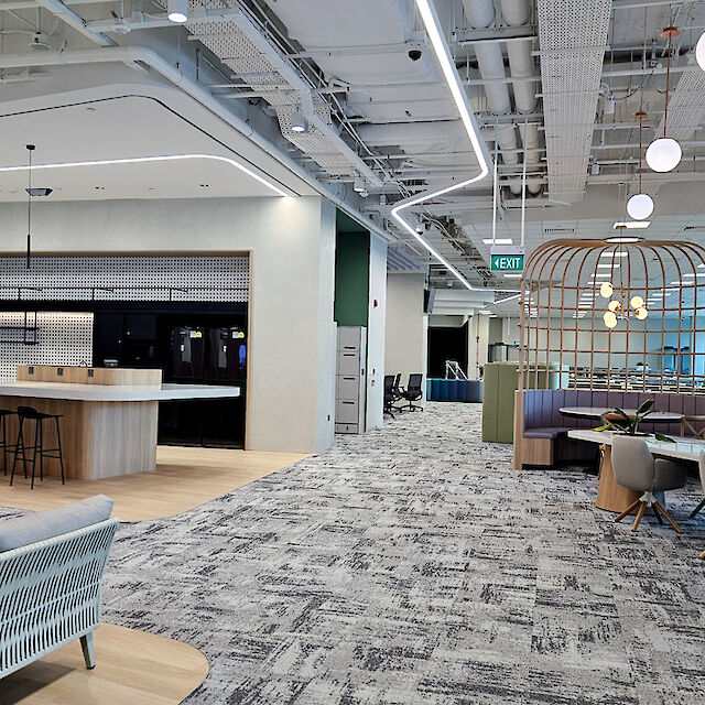 Modern office with lounge, open kitchen, meeting areas, and curved light lines on the ceiling
