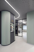 Curved liquid line on perforated ceiling, sage green walls, modern practice hallway with glass partition