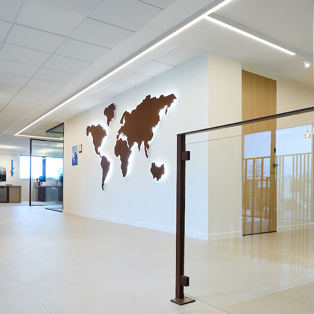 Entrance area with world map on the wall and linear ceiling lighting in the renovated Apageo headquarters