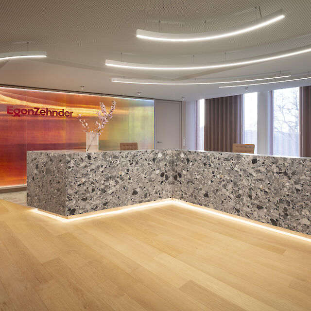 Modern reception area with coloured glass wall and curved Liquid Line light lines on the ceiling