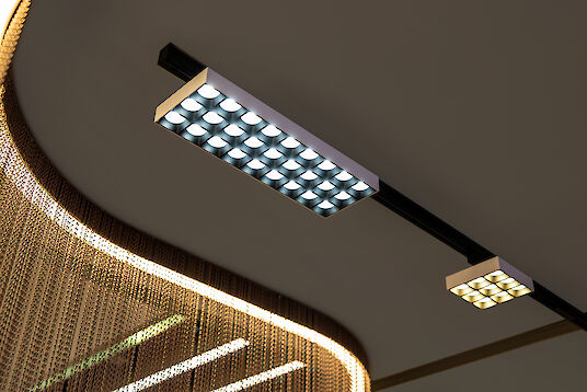 Rectangular and square LED modules in rail mounting, visible in front of illuminated chain curtain