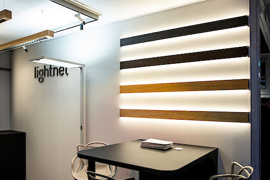 Illuminated Matric lights with wood paneling on the wall, next to them a table and chairs in the Lightnet booth